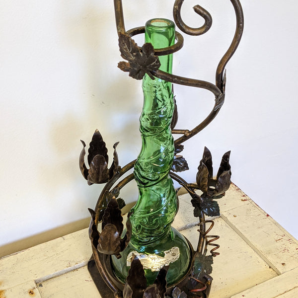 metal wine bottle holder with flowers and green vintage wine bottle/ vase close up